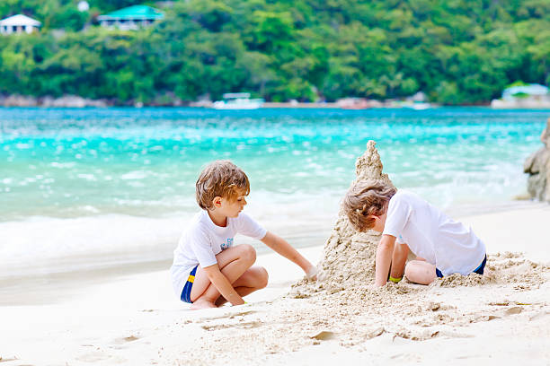 istock Two kid boys building sand castle on tropical beach 610989386