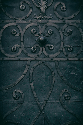 Dark, low key metal surface with decor from the exterior of an 18th century church door.