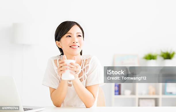 Young Woman Drinking Coffee In Living Room Stock Photo - Download Image Now - Women, Coffee - Drink, Asian and Indian Ethnicities