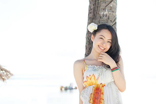 istock Japanese woman under palm tree on the beach 610991020