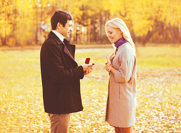 istock romantic couple outdoors man proposes woman marry red box ring 611064584