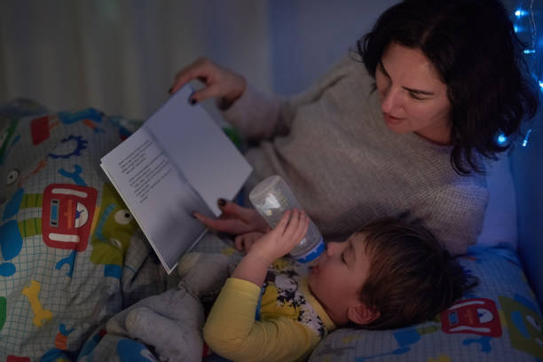 siempre tiene su botella y un libro a la hora de acostarse - child bedtime imagination dark fotografías e imágenes de stock