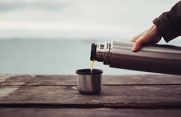 Traveler pouring tea from thermos stock photo