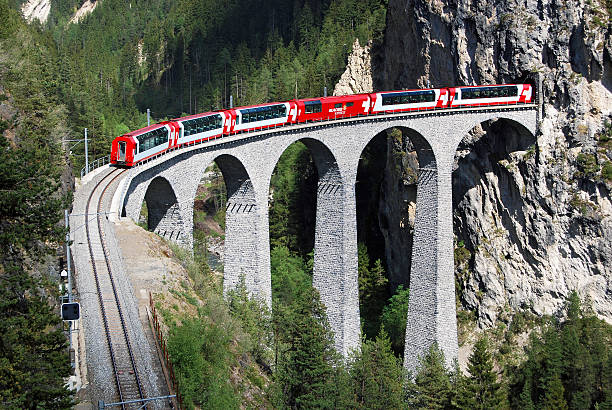 Glacier Express just before Filisur station Filisur Switzerland - Aug 13, 2011: In the summer of 2011 is this with swiss flags decorated Glacier Express on its way from Zermatt to St. Moritz. The train crossing the famous Landwasser viaduct just before Filisur station in canton of Graubünden. gotthard pass stock pictures, royalty-free photos & images