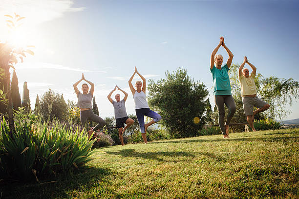 senior yoga class outdoor - yoga exercising outdoors group of people foto e immagini stock