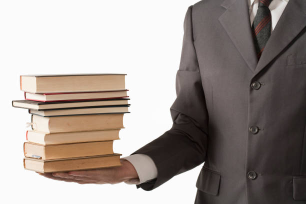 istock Man in suit holding stack of books 611074468