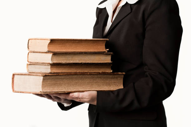 istock Woman in suit holding large old books 611074502