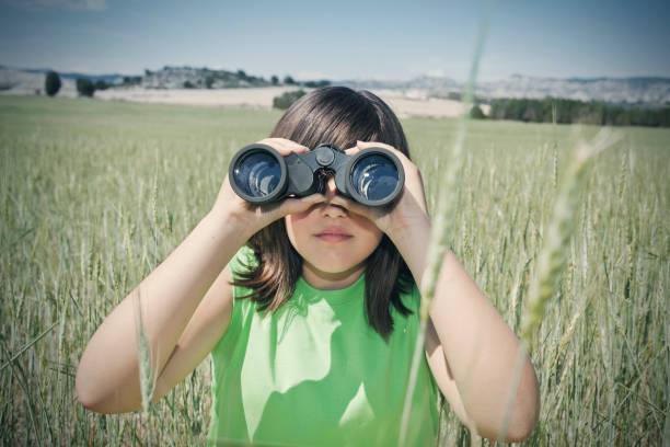 istock Girl looking with binoculars in green field 611076654