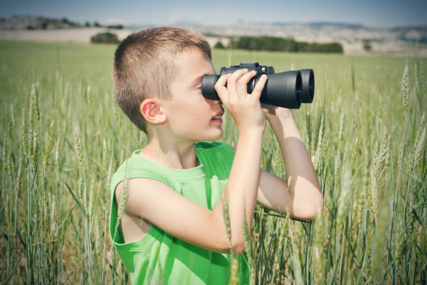 istock Boy looking with binoculars in green field 611076658