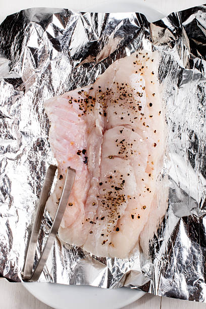 istock raw hake with crushed peppercorn on aluminum foil 611077346