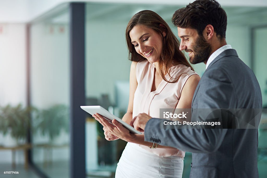 Positivity inspires productivity Shot of a young businessman and businesswoman using a digital tablet together in an office Business Person Stock Photo