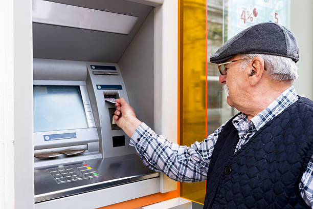 elderly man inserting credit card to ATM elderly man inserting credit card to ATM outdoor cashpoint stock pictures, royalty-free photos & images