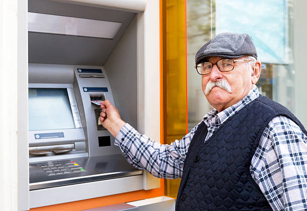 istock elderly man inserting credit card to ATM 611077600