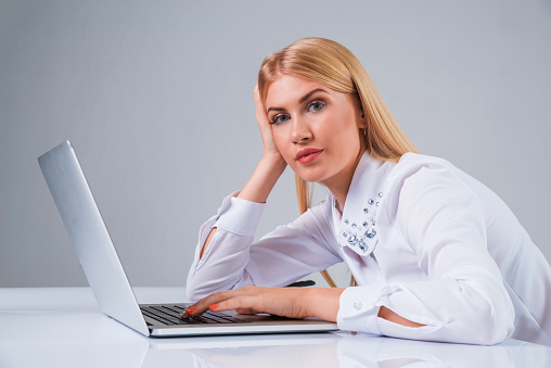 Young businesswoman working at laptop computer. tired, hunched, pleased