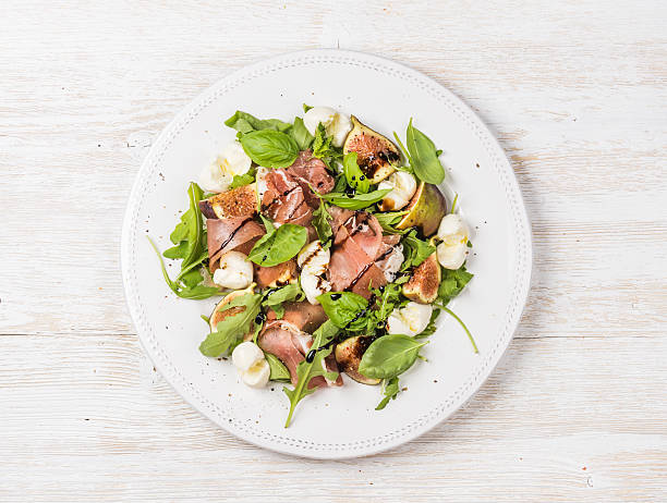 istock Prosciutto, arugula, basil, figs salad and glass of red wine 611079730