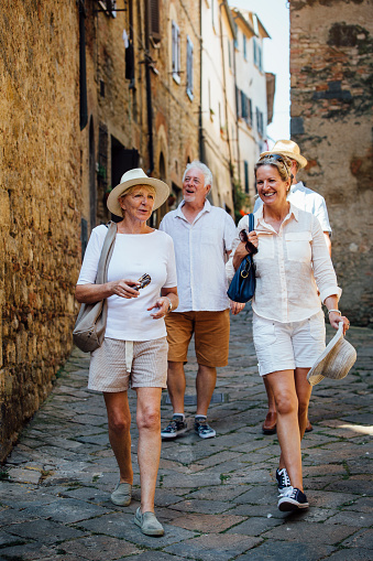 Mature couples looking around old town Italy. They walk down a narrow street while on holiday.