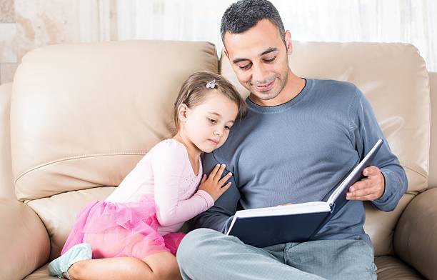 istock Little Girl And Father Reading Book 611083654