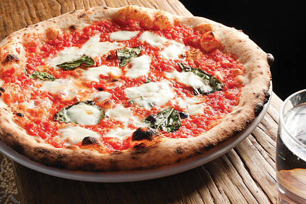 istock Simple pizza made with tomatoes and mozzarella cheese on wooden 611084180