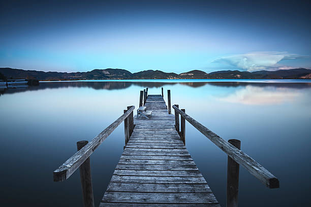 istock Wooden pier or jetty  blue lake sunset and sky reflection 611084532