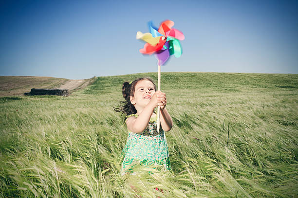 Girl playing with toy windmill in barley field