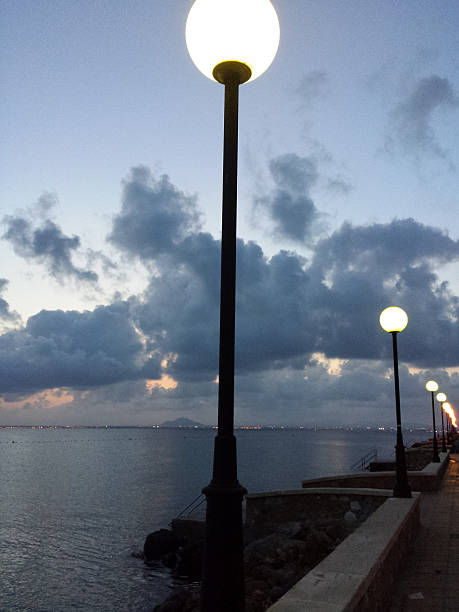 istock Calm sea with clouds reflected in the water and lamppost 611091572