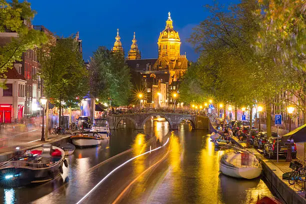 Night red-light district De Wallen, canal, Basilica of Saint Nicholas and bridge, Amsterdam, Holland, Netherlands. Long exposure.