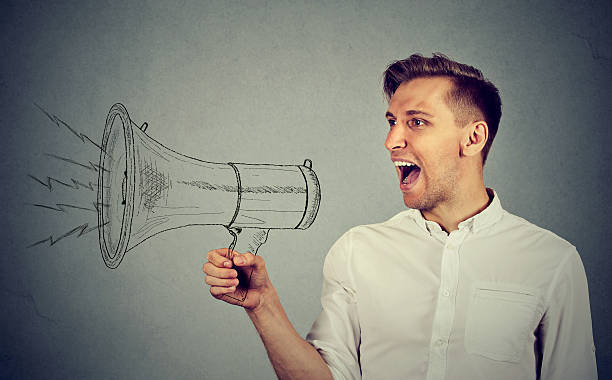 istock young man holding screaming in megaphone 611093016