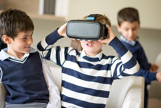 istock Little boy trying virtual reality eyeglasses device with friends 611093294