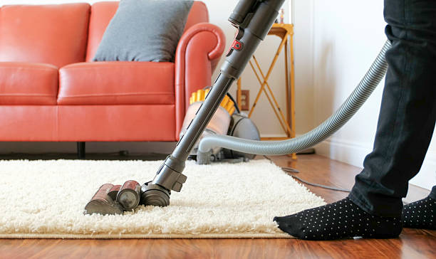 Vacuuming A woman vacuuming a rug/carpet in a home living room. shag rug stock pictures, royalty-free photos & images