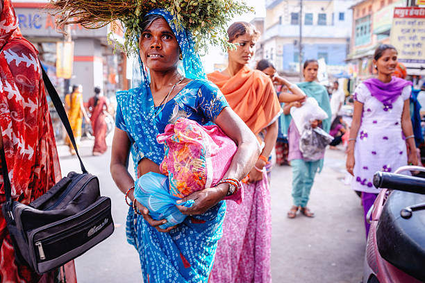 Udaipur, India - March 12, 2014: Indian woman walking on street in India in traditional colorful outfits.