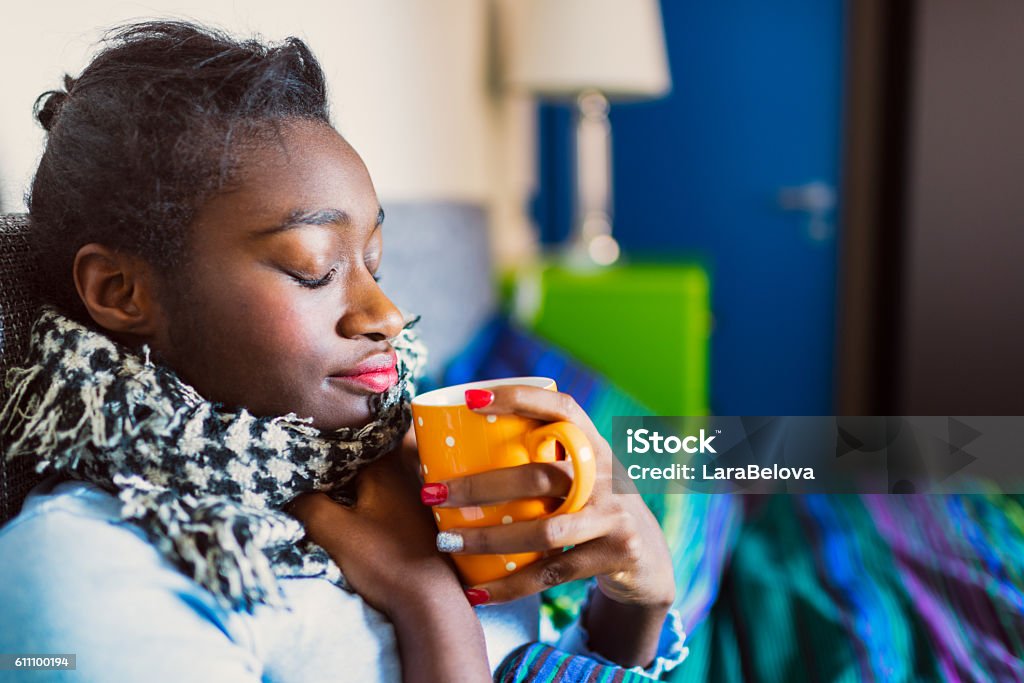 Young sick African woman in bed Sore Throat Stock Photo