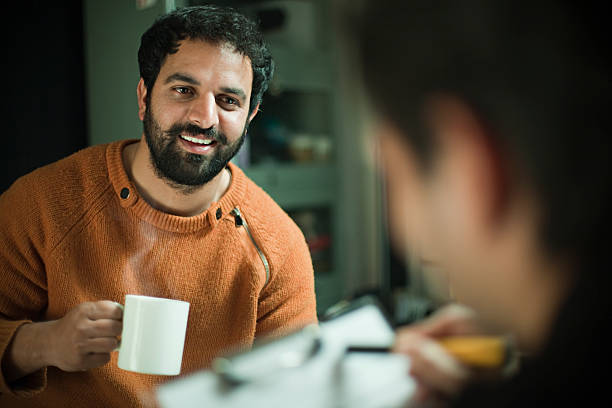 Happy young men discussing business on clipboard and enjoying coffee. stock photo