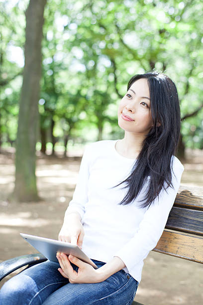 istock Japanese woman using a tablet in a park 611107504