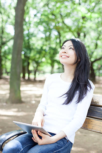 istock Japanese woman using a tablet in a park 611107532