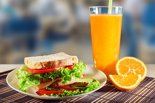 Sandwich with salami, cheese and salad and orange juice