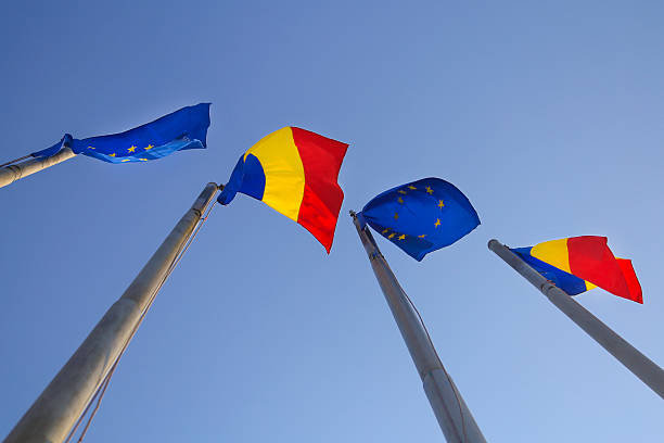 Four flag poles with flags of Romania and European Union.