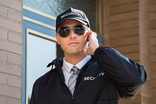 istock Young Security Guard Standing In Front Of The Entrance 611109632