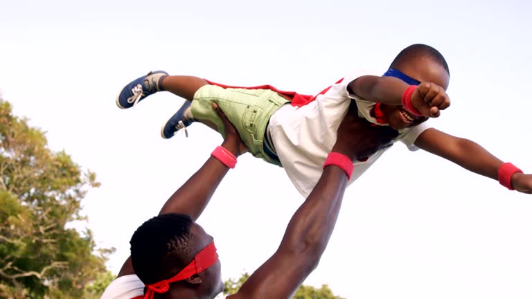 Man carrying his son in costume of superheroes