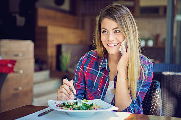 istock Young girl is talking using her mobile phone in restaurant 611170870