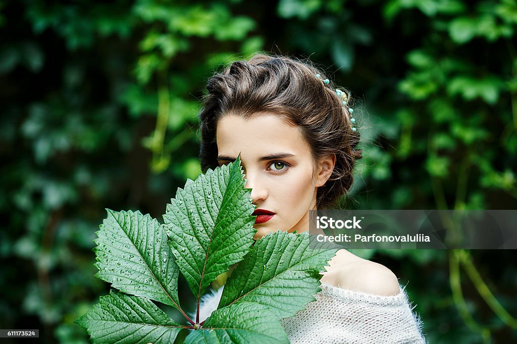 Portreit of young girl with grape leaf in her hand Portrait of a young slim beautiful girl with retro hair wearing a white blouse, blue skirt, posing against a background of vineyard Women Stock Photo