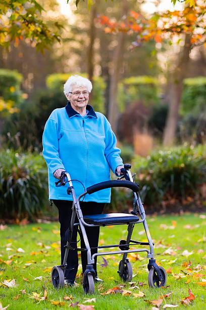 istock Senior lady with a walker in sunny autumn park 611174236