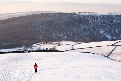 Woman walking in snow covered countryside, Peak District, UK