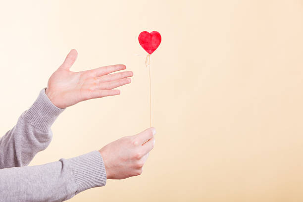 istock Male hand with little heart on stick. 611176668