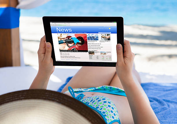 istock Woman Reading News At Beach 611177562