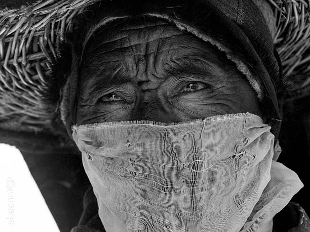 Kursha, India - July 17, 2012: A monk with eyes like gimlets and piercing hypnotic gaze performs a religious mask dance during the Cham Dance Festival in Kursha monastery, Zanskar, India. Black and white photo.