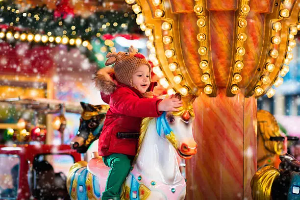 Photo of Child riding carousel on Christmas market