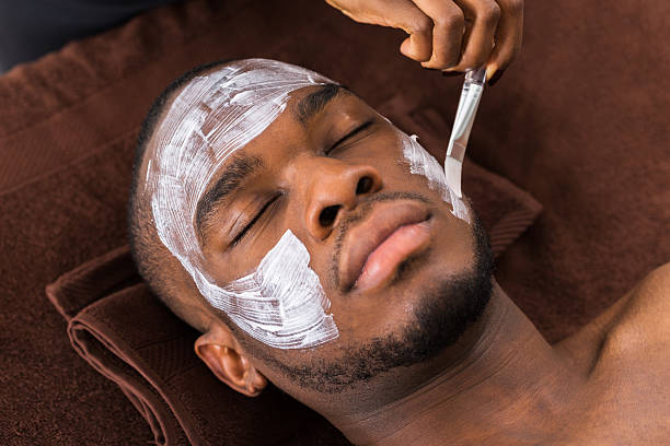 kosmetikerin anwenden gesichtsmaske auf mann - kosmetikmaske fotos stock-fotos und bilder