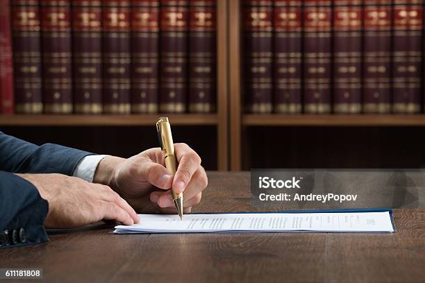 Lawyer Writing On Legal Documents At Desk Stock Photo - Download Image Now - Book, Writing - Activity, Law