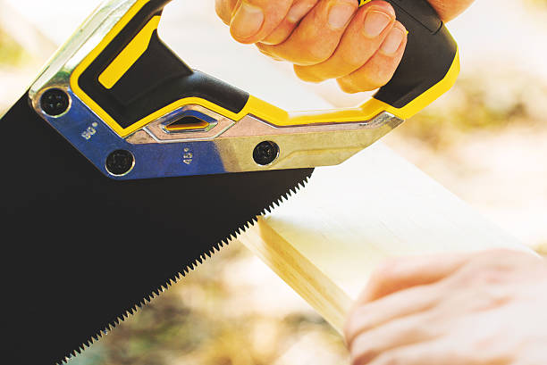 istock Man sawing a wood board outdoors 611182932