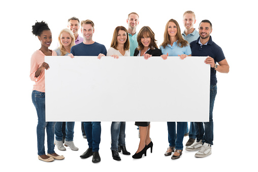 Full length portrait of confident creative business team holding blank billboard against white background